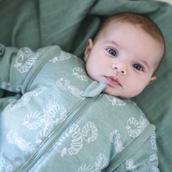 Bebé desperto no seu saco de dormir verde com mangas