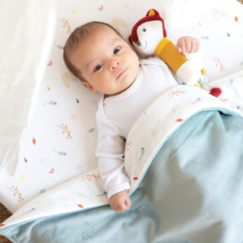 Baby liegt unter seiner blauen Samtdecke Versteckspiel im Wald