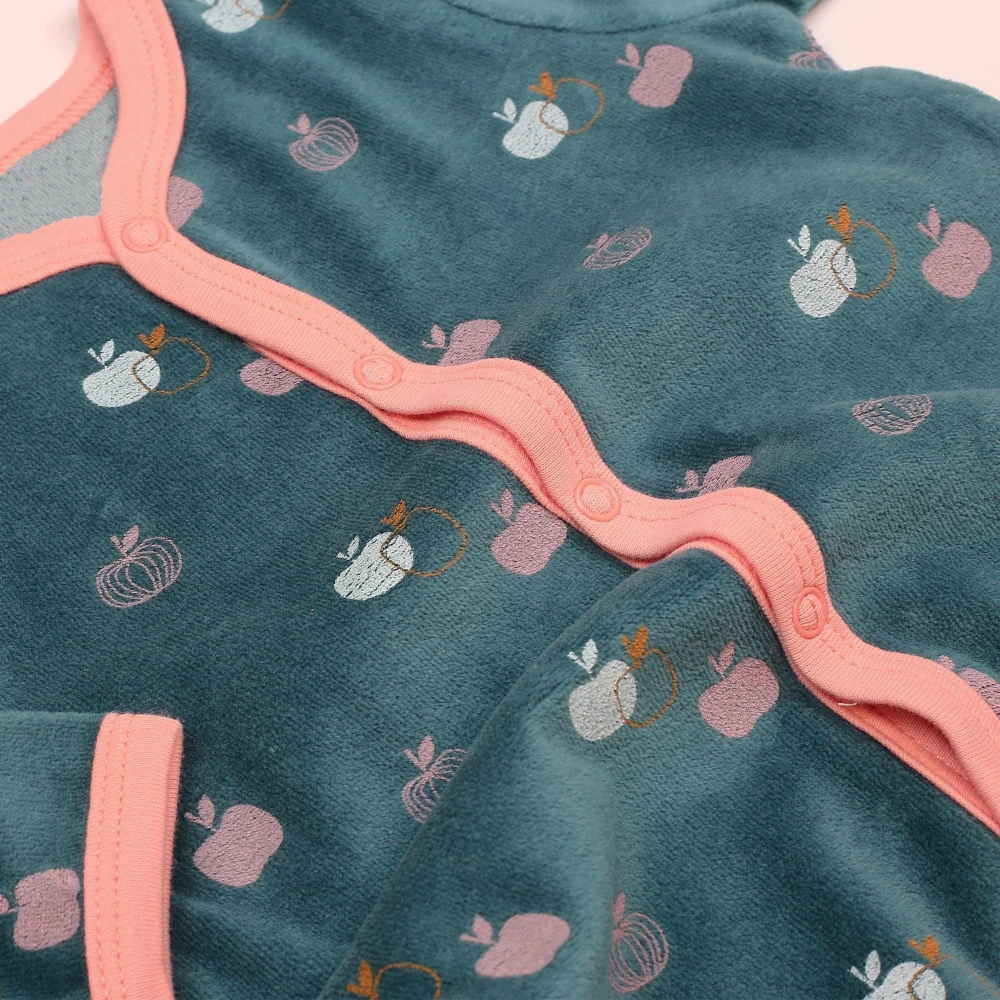 Zoom nos motivos de maçãzinhas e o material veludo do pijama