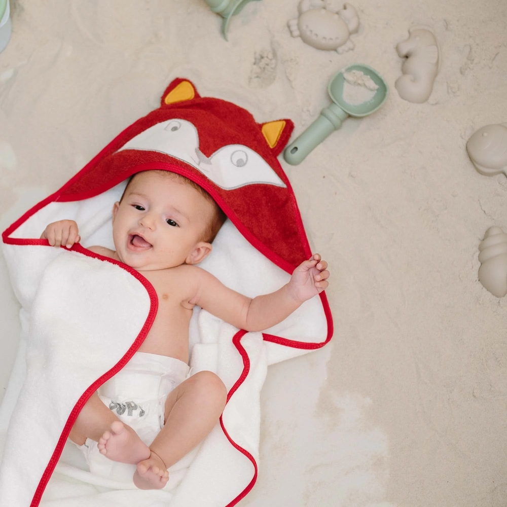 Baby girl with hooded towel lying in the sand. Baby girl with hooded towel lying in the sand.