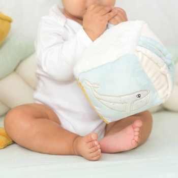 Bebé jugando con su cubo de estimulación sentado sobre su alfombra