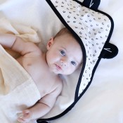 Petit bébé allongé dans sa cape de bain Léopard en coton Petit bébé allongé dans sa cape de bain Léopard en coton