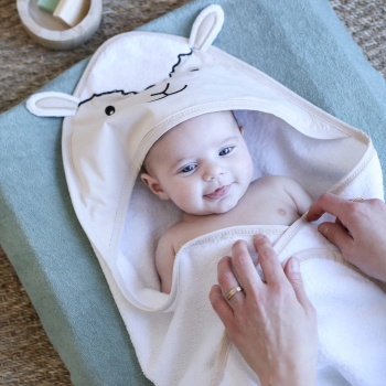 Mama, die ihr Baby mit dem beigen Bademantel mit kleinen Schafohren abtrocknet