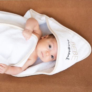 Baby lekker warm in zijn badcape op zijn aankleedkussen Baby lekker warm in zijn badcape op zijn aankleedkussen