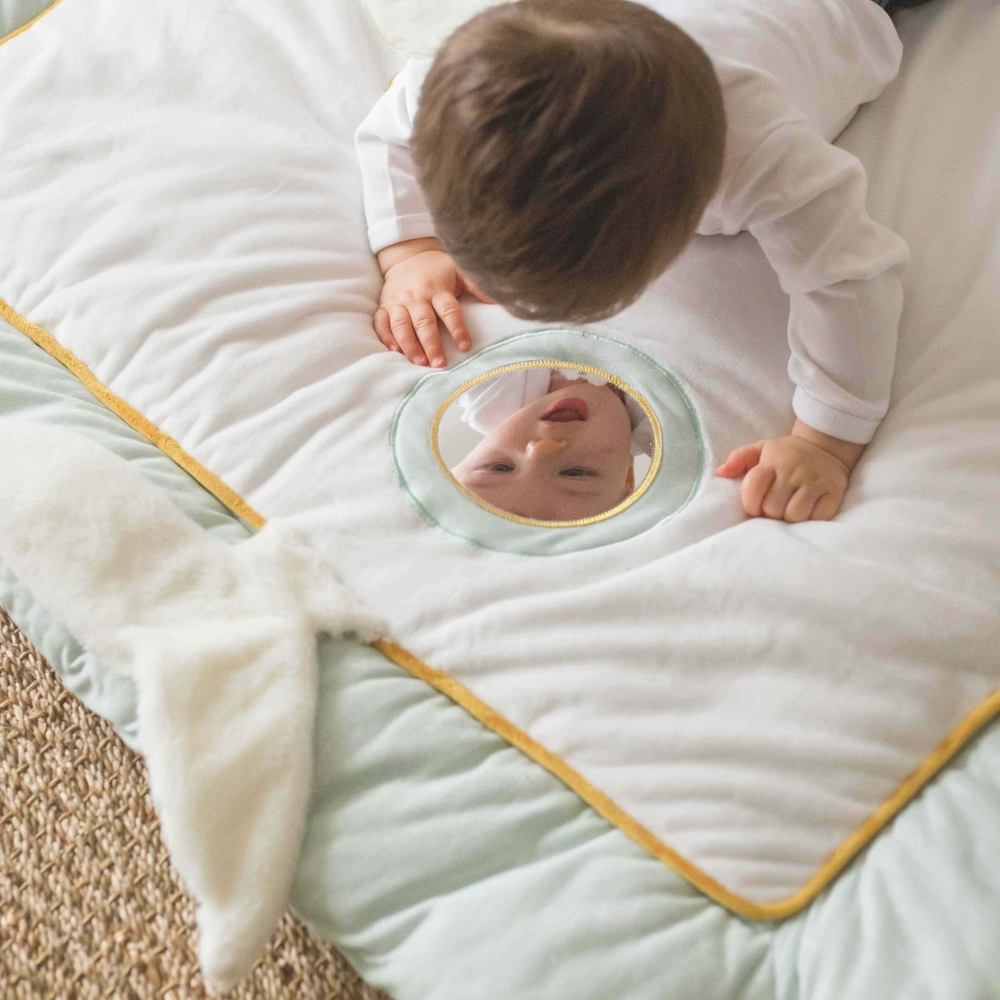 Baby looking at themselves in the play mat mirror Baby looking at themselves in the play mat mirror