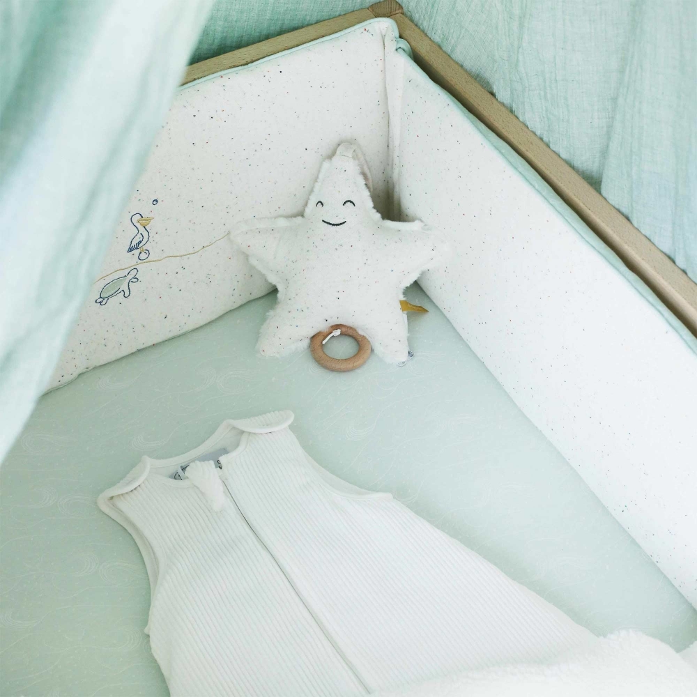 saco de dormir de recém-nascido numa cama de bebé com ambiente oceano