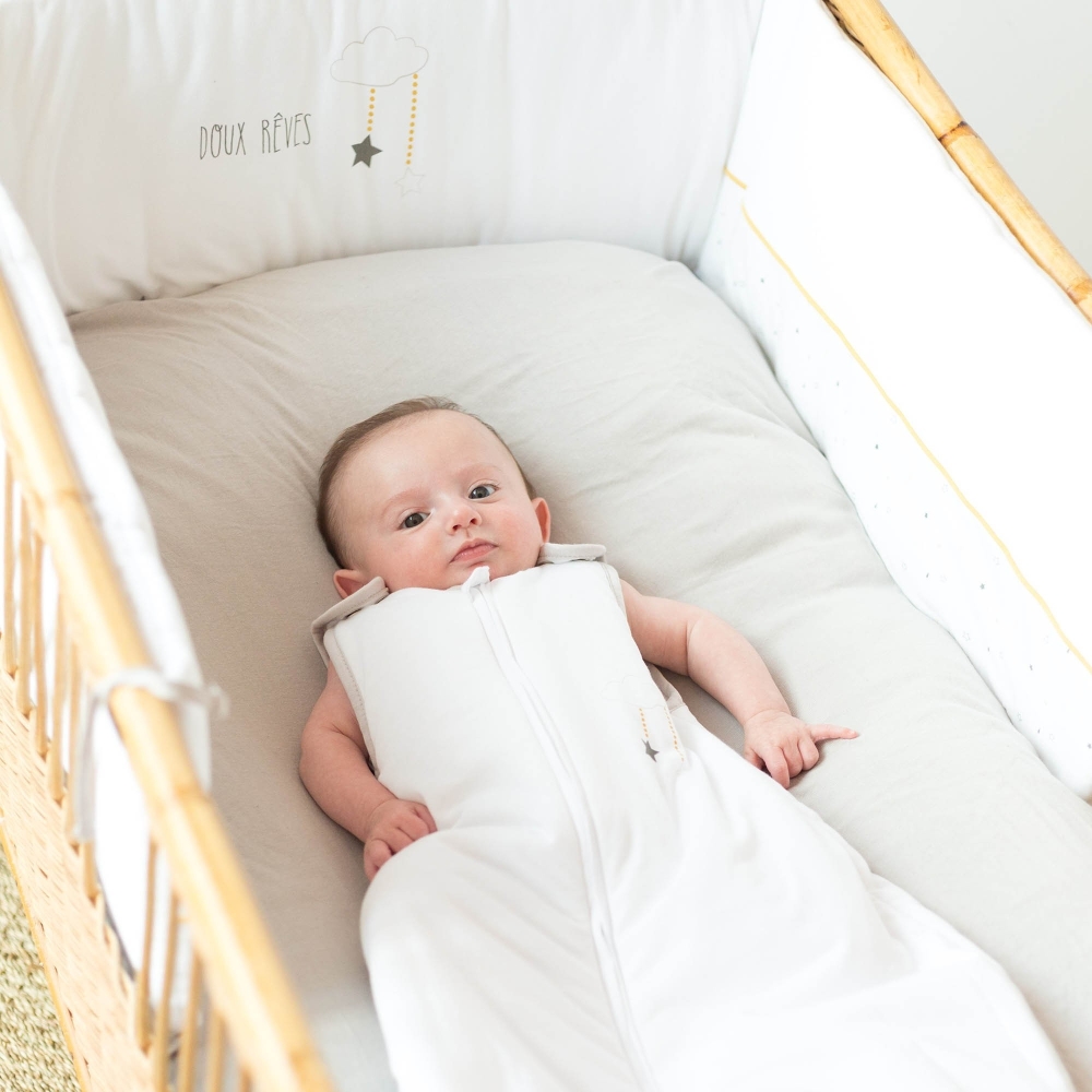 Baby in seinem Bett mit Schlafsack und Bettumrandung