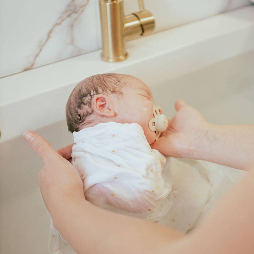 bébé apaisé dans son bain emmailloté