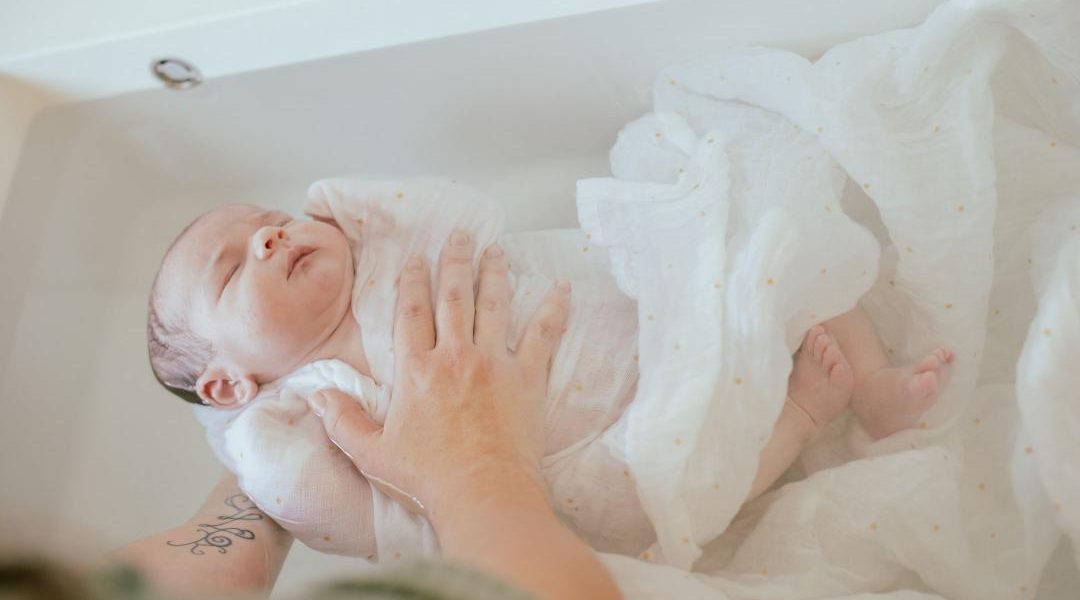 bebe dans son bain enveloppé dans un lange