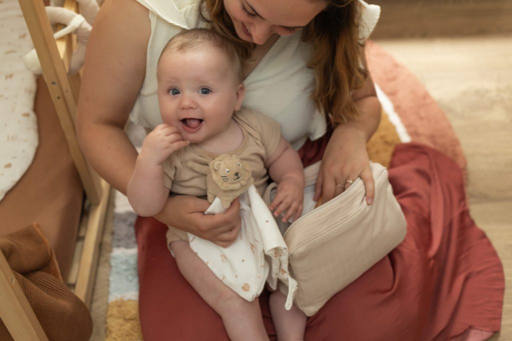 maman et son bébé qui jouent avec un doudou lion